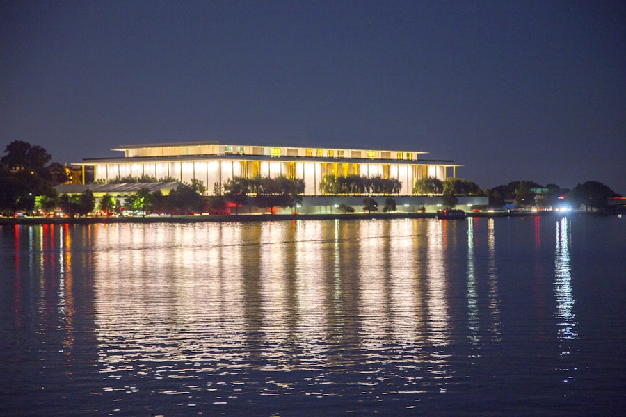 The Kennedy Center illuminated at night, reflecting on the Potomac River.