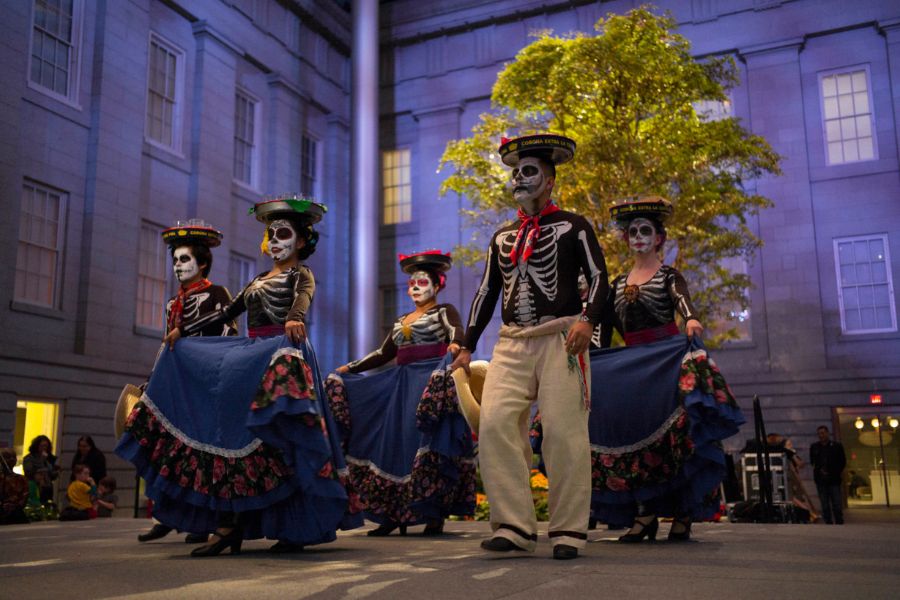 Dancers in traditional Día de los Muertos attire, with colorful skirts and skeleton face paint, perform at the Smithsonian American Art Museum in Washington, DC.