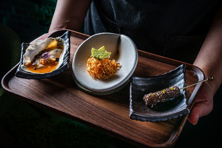 A tray featuring three elegant dishes, artfully presented on unique ceramic plates.