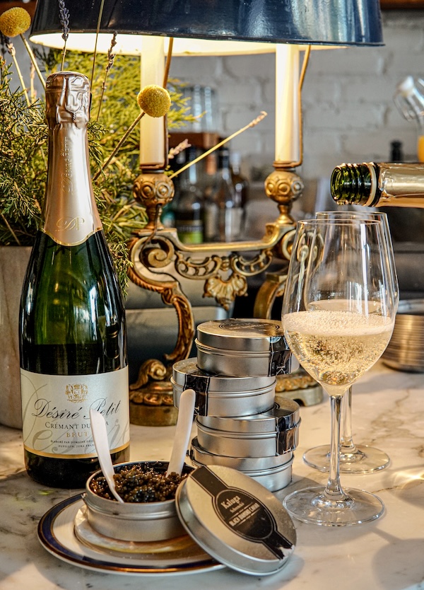 A glass of champagne is poured beside tins of Kaluga caviar arranged on an elegant bar setup in Washington, DC.