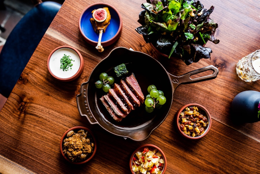 A beautifully plated spread of seasonal dishes is arranged on a wooden table at a Washington, DC restaurant.