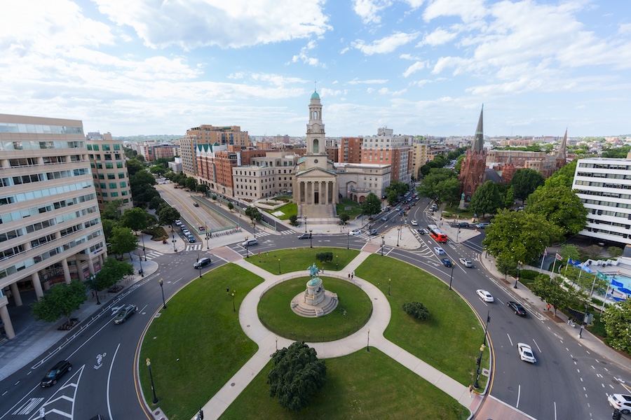An aerial view shows Thomas Circle with its central statue surrounded by busy Washington, DC streets.