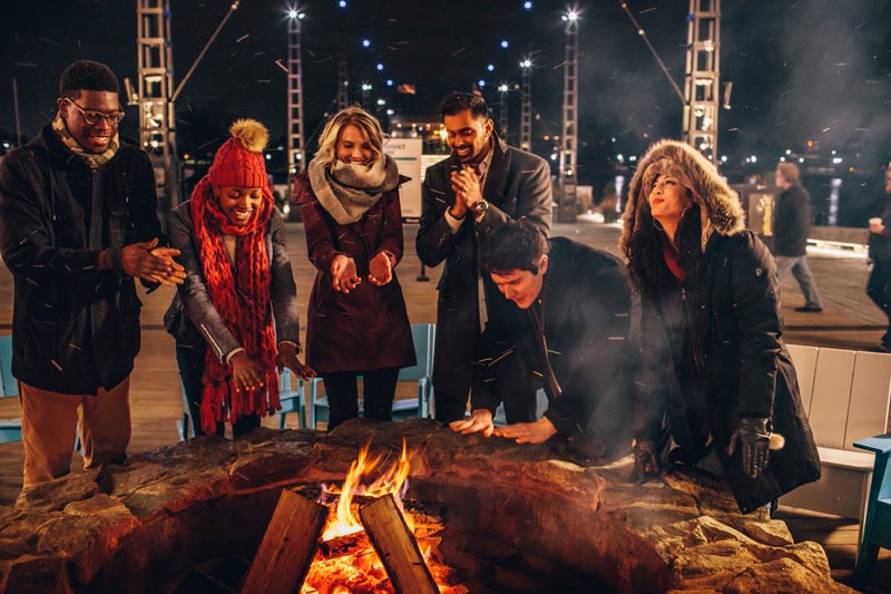 Friends gathered around the fire at The Wharf - Ways to make the most of Winter in Washington, DC