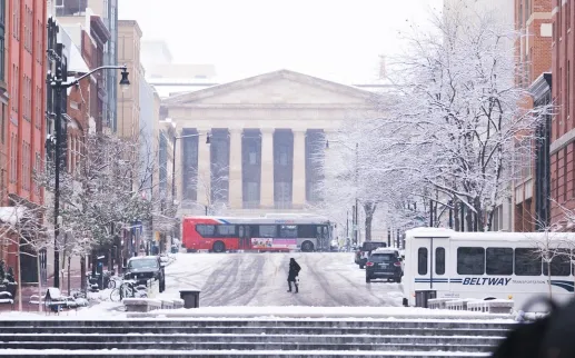 A snowy scene of a downtown street leading up to the National Archives in Washington, DC. 